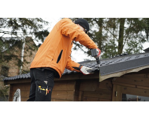 Vakman monteert dakleer op een tuinhuis met een accuschroevendraaier.