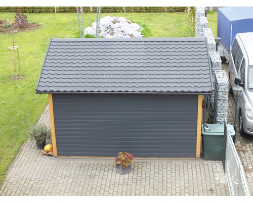 Garage met grijze roldeur en pannendak in de tuin