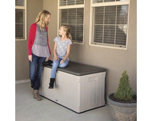 Een moeder staat naast een meisje dat op een kunststof tuinkist zit.