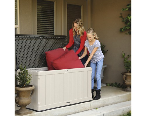 Moeder en dochter bergen kussens op in een kunststof tuinkist.