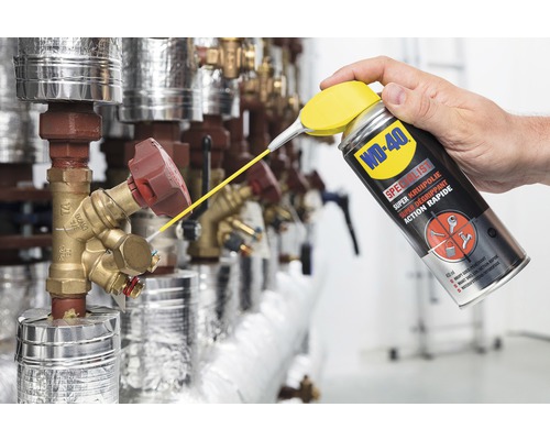 Een persoon spuit WD-40 multifunctionele olie op een ventiel.