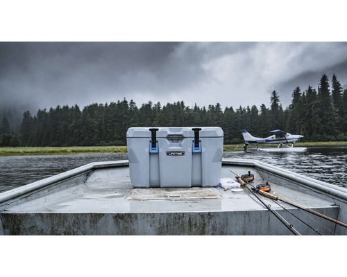 Koelbox op een boot met vishengels en een watervliegtuig op de achtergrond