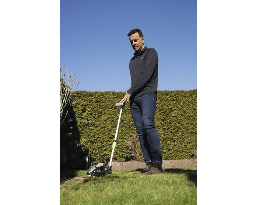 Man snijdt gazonranden met een gazonrandtrimmer in de tuin.