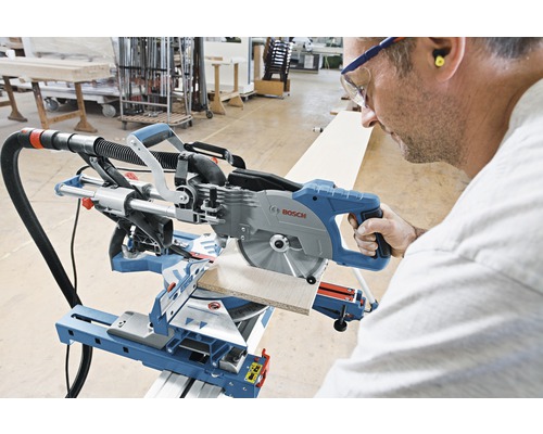 Een persoon bedient een Bosch afkort- en verstekzaag bij het zagen van een werkstuk.