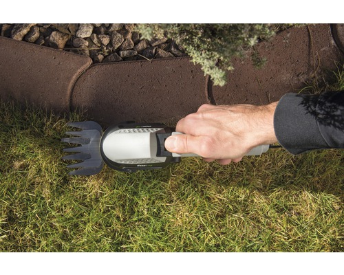 Hand houdt graskantsnijder vast bij het trimmen van gras langs een stoeprand.