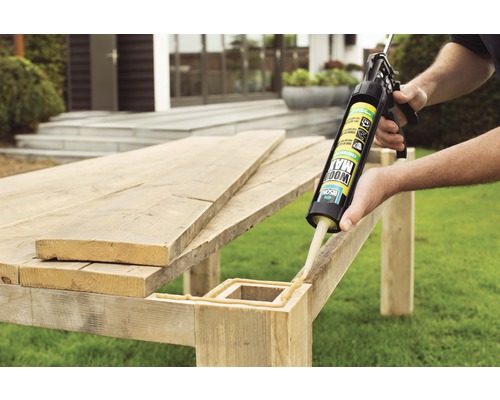 Buitenfoto van een persoon die met een kitspuit houtlijm aanbrengt op een werkstuk.