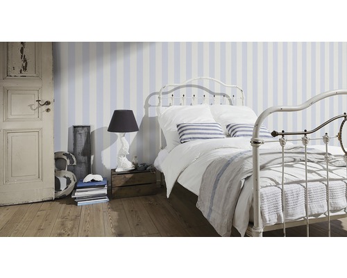 Slaapkamer met gestreept behang, metalen bedframe en houten vloer