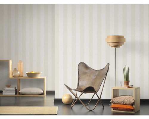 Woonkamer met gestreept behang, fauteuil, staande lamp en planken voor decoratie