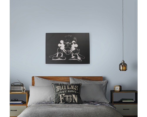 Slaapkamer met bed, nachtkastjes, lamp en muurdecoratie met Mickey Mouse-motief