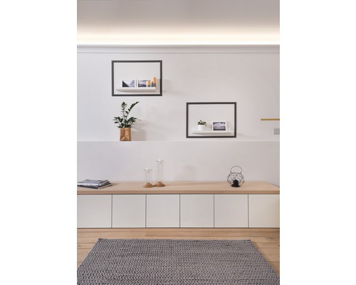 Woonkamer met houten vloer, grijs vloerkleed, dressoir en wandplanken