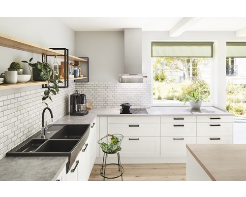 Lichte keuken met spoelbak, kraan, rekken en keukenapparatuur.