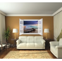 Woonkamer met bank, fauteuil, kamerplant, vloerkleed en vensterwandafbeelding met strandthema