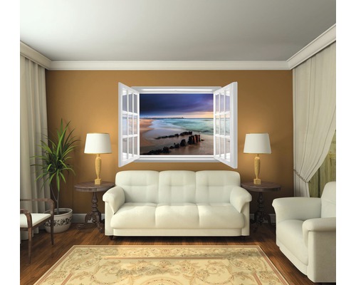 Woonkamer met bank, fauteuil, kamerplant, vloerkleed en vensterwandafbeelding met strandthema