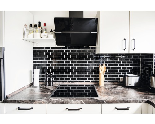 Moderne keuken met zwarte tegels, afzuigkap en kookplaat