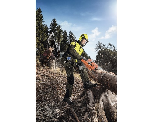 Bosarbeider met veiligheidsuitrusting en kettingzaag aan het werk in het bos