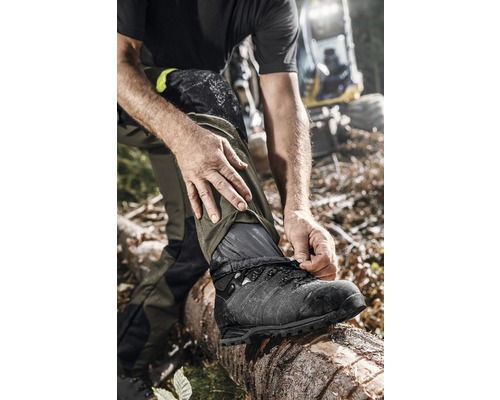 Man bindt veters aan werkschoenen in bos