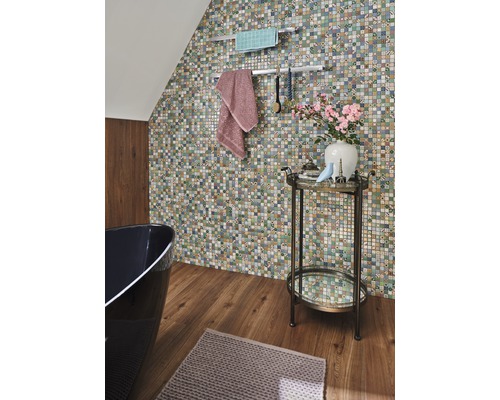 Badkamer met mozaïekmuur, bad, handdoeken en bijzettafel