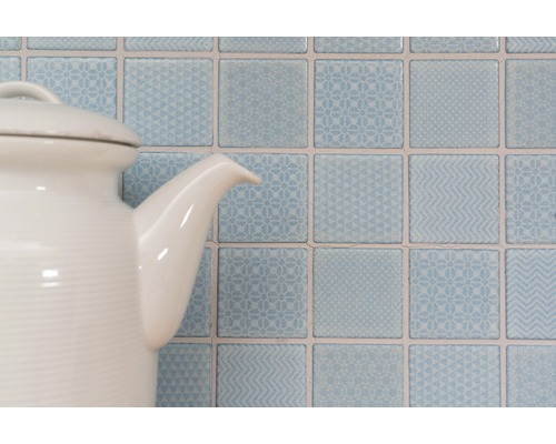 Decoratieve vierkante wandtegels met patronen achter een theepot