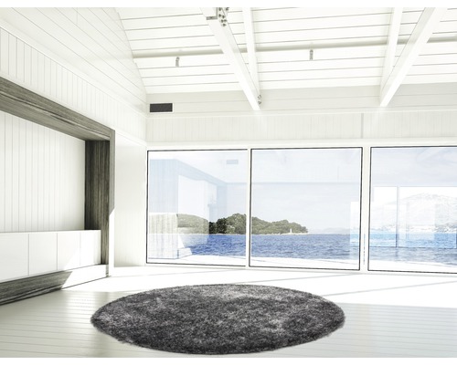 Lichte kamer met grijs, rond vloerkleed, ramen en houten balkenplafond