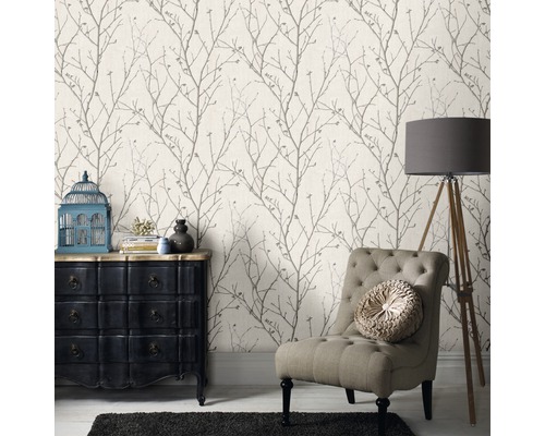 Woonkamer met patroonbehang, fauteuil, commode en vloerlamp