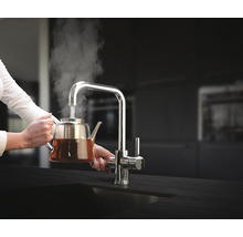Vrouw vult theepot met heet water uit kraan
