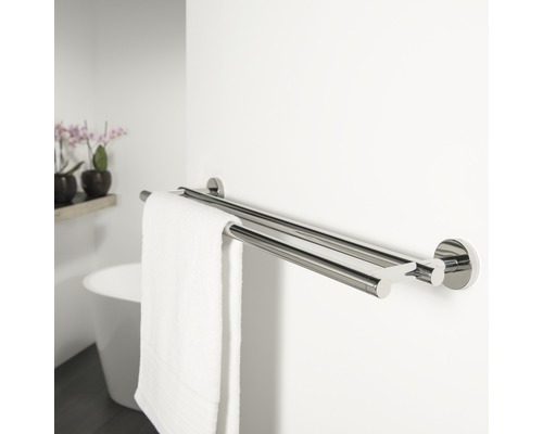 Dubbele metalen handdoekhouder aan een badkamermuur met een witte handdoek