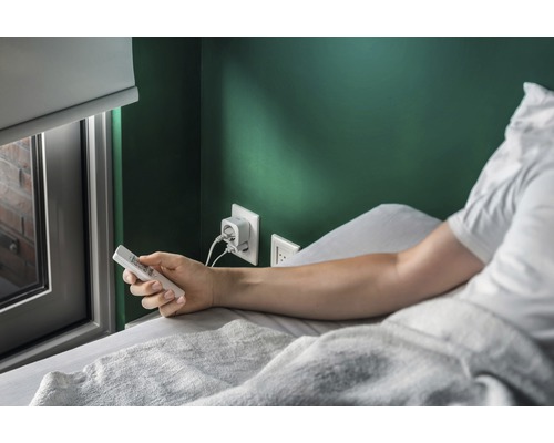 Scene van een man in bed met afstandsbediening en oplader in het stopcontact