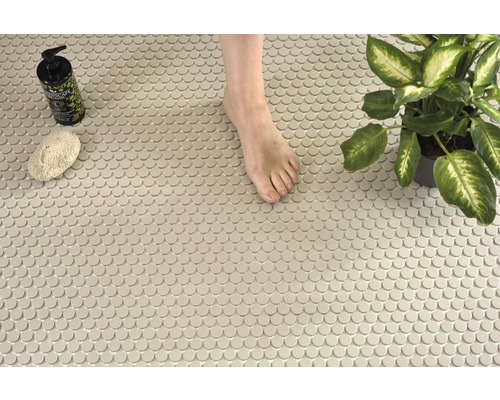 Scene met ronde mozaïektegels, een voet, een plant, een spons en een zeepfles