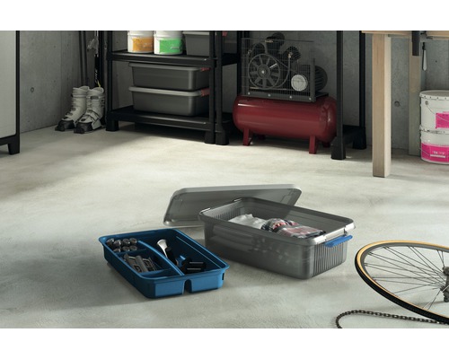 Scene met planken, werkplaatscompressor, verfemmers, skischoenen, fiets en twee opbergdozen