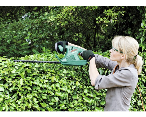 Vrouw snoeit haag met een heggenschaar van Bosch