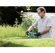 Man snoeit heg met een heggenschaar in de tuin
