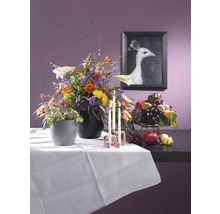 Arrangement met bloemen, fruit, kaarsen en een ingelijste foto van een witte pauw op een tafel