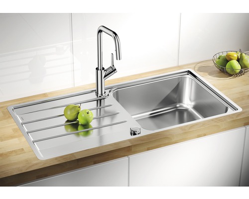 Spoelbak van roestvrij staal met afdruiprek en kraan op een werkblad