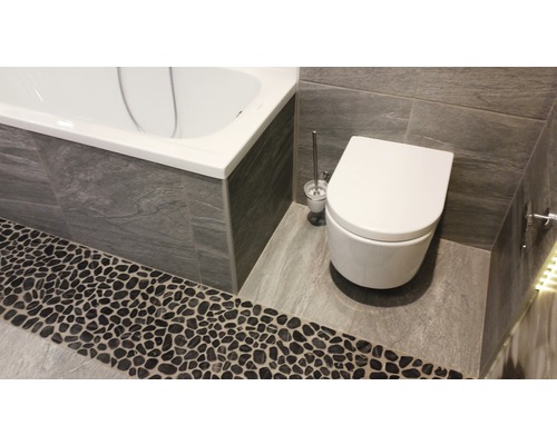 Badkamer met bad, toilet en stenen vloer
