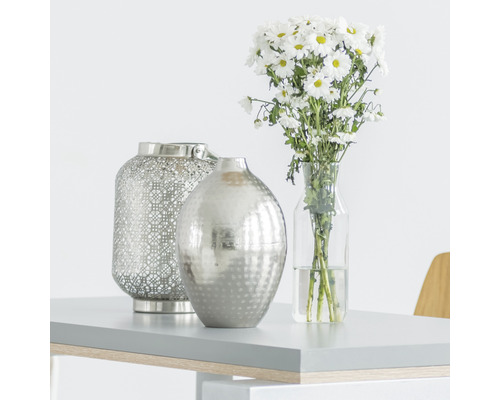 Decoratieve scène met windlicht, vaas en boeket op een tafel.