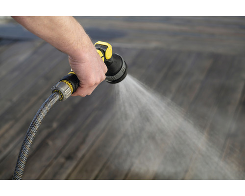 Persoon besproeit houten vloer met tuinslang en spuitpistool