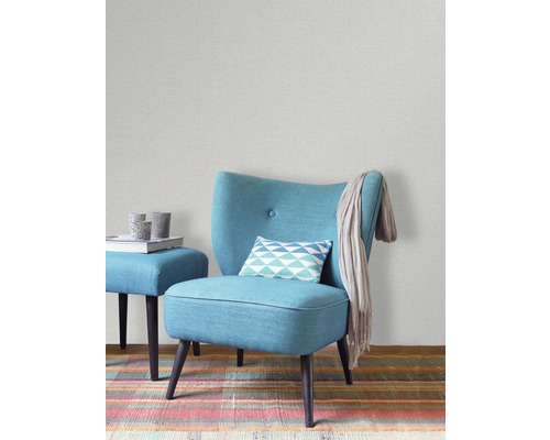 Interieurscène met lichtgrijs behang, turquoise stoel, kruk en kleurrijk tapijt