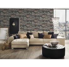 Woonkamer met bakstenen behang, hoekbank, voetenbanken, kast en decoratieve elementen voor een gezellige sfeer.