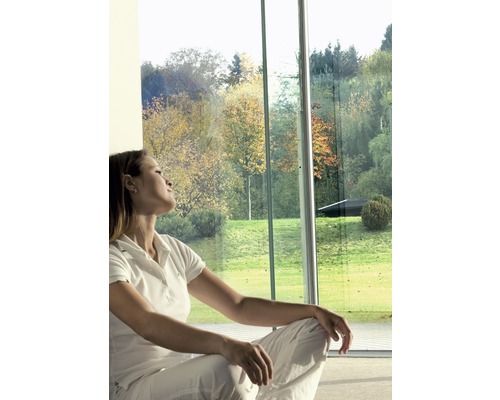 Vrouw zit voor een groot raam met uitzicht op een tuin