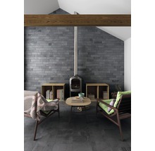 Woonkamer met open haard, twee fauteuils, salontafel, betegelde muur en betegelde vloer