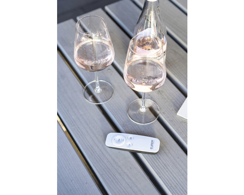 Twee wijnglazen en een fles wijn met een afstandsbediening op een houten tafel