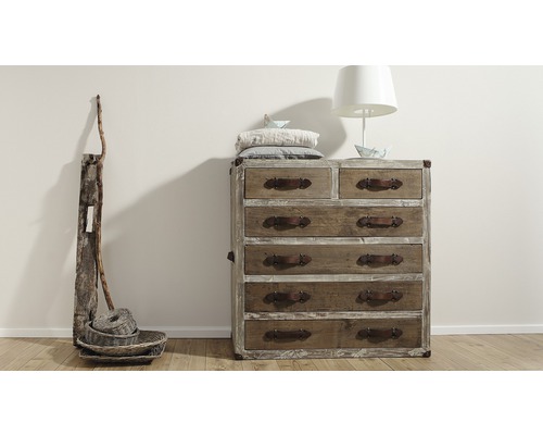 Ladekast met laden, lamp en decoratie op een houten vloer voor een muur
