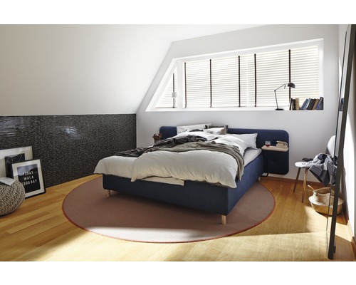Slaapkamer met bed, tapijt en decoratieve elementen op een lichte zolder