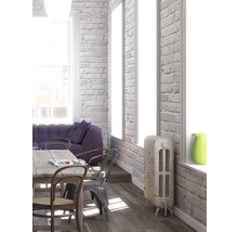 Lichte woonkamer met eettafel, stoelen, bank en radiator tegen een bakstenen muur