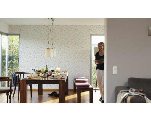 Lichte eetkamer met houten tafel, stoelen, bank en bloemenbehang.