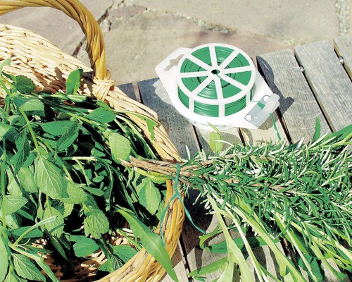 Plantbinders en mand met verse kruiden op houten tafel