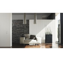 Moderne woonkamer met fauteuil, stenen muur en kamerplant