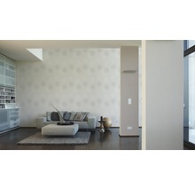 Woonkamer met bank, ottomane, vloerkleed en behang met motief