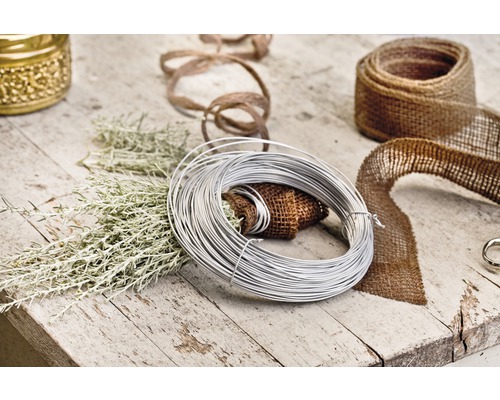 Decoratiescène met binddraad, jute lint en groene takken op een houten tafel