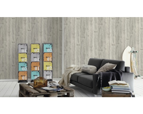 Woonkamer met grijs behang in houtlook, zwarte bank en kleurrijke metalen kasten ter decoratie.